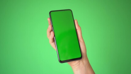 Woman hand holding the smartphone on green screen chroma key background. Mobile phone mock-up for your product.