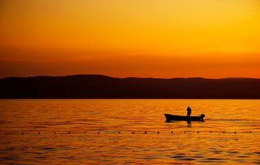 Poster - Image of a fishing boat against the sunset background