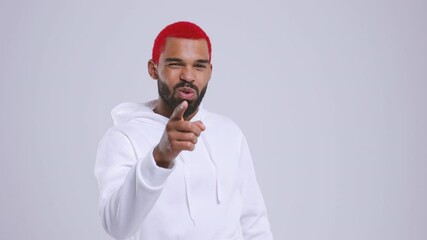 Wall Mural - Smiling young bearded african american man with red hair in hoodie isolated on white background studio. People lifestyle concept. Pointing index finger on camera doing phone gesture says call me back