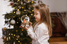 Girl Looking At A Glass Ball With A Scene Of The Birth Of Jesus Christ In A Glass Ball