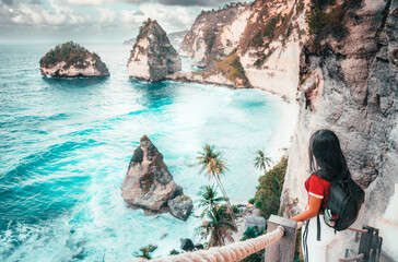 Traveler woman look at the ocean and rocks. Travel and Active lifestyle concept. Adventure and travel on Bali, Indonesia.