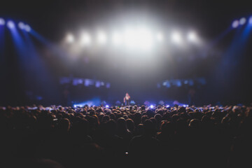 A crowded concert hall with scene stage lights, rock show performance, with people silhouette, colourful confetti explosion fired on dance floor air during a concert festival