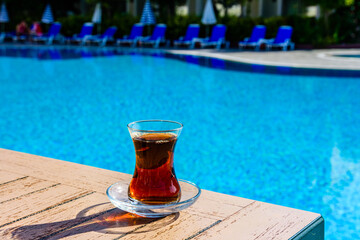 Black tea in traditional turkish glass on table near the swimming pool