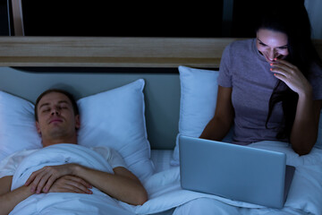 Woman sitting on bed in the night and using laptop computer