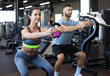© ty - Fit and muscular couple focused on lifting a dumbbell during an exercise class in a gym.