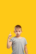 © golubovy - Creative idea. Promotional background. Aha moment. Solution discovery. Portrait of inspired surprised young boy in gray gained insight pointing up isolated on orange copy space.