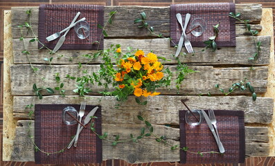 Thanksgiving background. Autumn table setting for a Thanksgiving party or gala dinner.Plate, cutlery, yellow floral and seasonal decorations on rustic wooden table