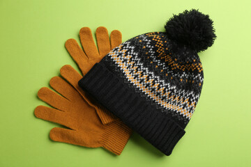 Poster - Woolen gloves and hat on green background, flat lay