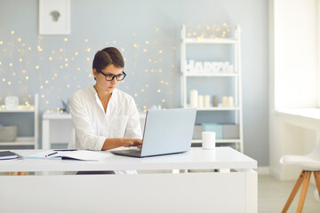 Wall Mural - Business lady in glasses sitting at home and working on laptop online