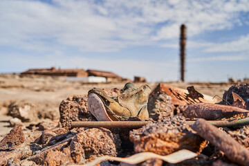 Wall Mural - old worn down shoe with an abandoned saltpeter mining town in the blurry background the Atacama desert of Chile, South America