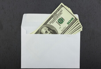 Dollars lie in a white envelope on a black background