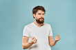 © SHOTPRIME STUDIO - Man gestures with his hands emotions displeasure white t-shirt blue background