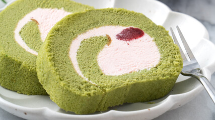 Delicious Matcha Swiss Roll Cake slices with strawberry cream on white background.