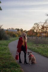 Wall Mural - Schöne Frau mit Roten Mantel und Hund im Goldenen Herbst beim Gassi gehn