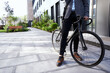 Cropped shot of stylish mature businessman standing with his bicycle near modern office building outdoors