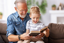 Happy Grandfather Reading Book To Grandson.