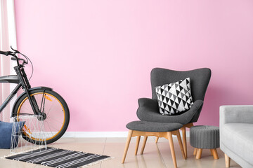 Stylish armchair and ottoman with bicycle in interior of room