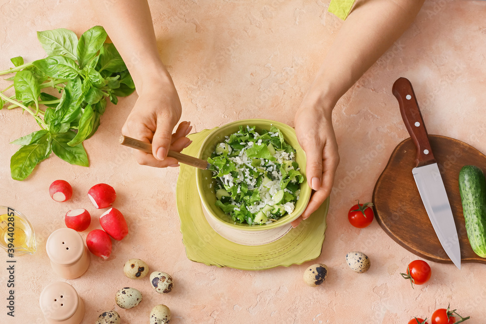 Woman mixing rice salad with vegetables on table