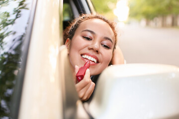 Canvas Print - Beautiful African-American woman applying lipstick while sitting in car