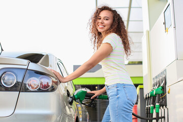 Canvas Print - African-American woman filling up car tank at gas station