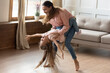 © fizkes - Happy mother circling little daughter in dance, active mommy her preschool funny kid girl dancer having fun listen funky music enjoy playtime on weekend at home. Hobby activity, leisure time concept