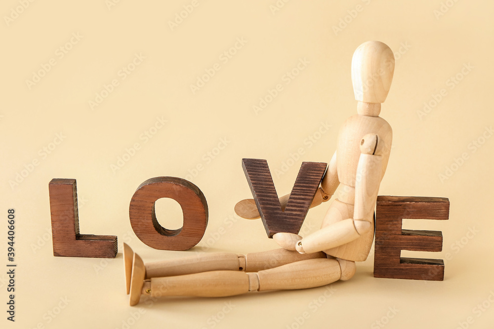 Wooden mannequin with word LOVE on color background