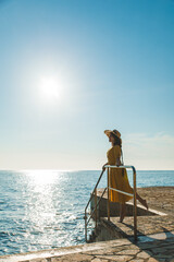 Wall Mural - young pretty woman in yellow sundress at sea beach