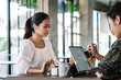 © amnaj - Two young asian woman using digital tablet while sitting in coffee shop.