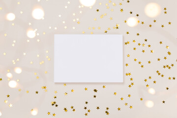 Festive gold background. Empty paper blank, shining stars confetti and fairy lights on beige and Set Sail Champagne background. Christmas. Wedding. Birthday. Flat lay, top view, copy space