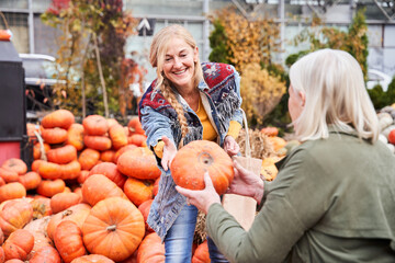 Woman passes pumpkin from hand to hand to her senior mother