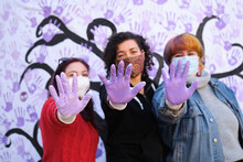Three Women With Their Hands Painted Purple Participating In The International Day For The Elimination Of Violence Against Women Participatory Mural. 25 November.