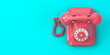 Pink vintage rotary telephone on mint green background.