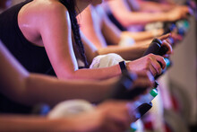 Cropped Image Of Shoulders And Arms Of Woman On A Bike In A Spin Class
