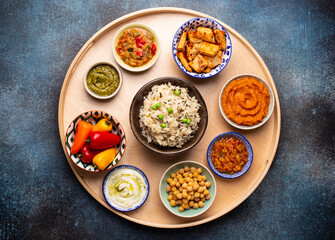 Wall Mural - Indian Thali - selection of various dishes served on round wooden platter. Assorted Indian vegetarian meze with boiled basmati rice, paneer, dal, chutney in different bowls. Top view