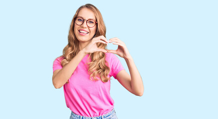 Poster - Young beautiful caucasian woman with blond hair wearing casual clothes and glasses smiling in love doing heart symbol shape with hands. romantic concept.