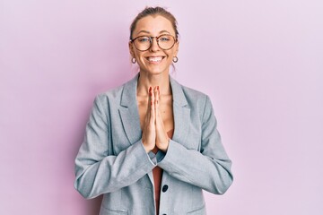 Poster - Beautiful caucasian woman wearing business jacket and glasses praying with hands together asking for forgiveness smiling confident.