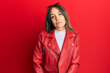 Wall Mural - Young brunette woman wearing red leather jacket angry and mad raising fist frustrated and furious while shouting with anger. rage and aggressive concept.