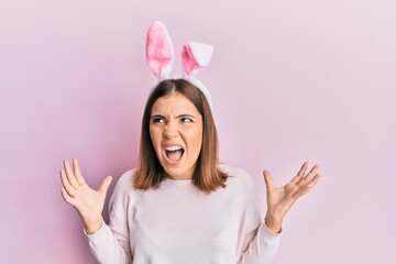 Canvas Print - Young caucasian woman wearing cute easter bunny ears showing and pointing up with fingers number three while smiling confident and happy.