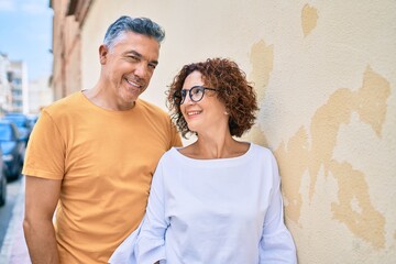 Sticker - Middle age couple smiling happy leaning on the wall at street of city.