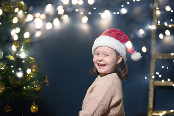 Christmas, holidays and childhood concept - cuti little girl having fun near the Christmas tree.