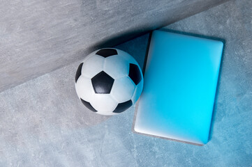 Soccer and football ball and grey laptop on grey background. Online workout concept