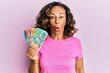 © Krakenimages.com - Middle age hispanic woman holding australian dollars scared and amazed with open mouth for surprise, disbelief face