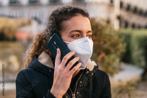 New normal. Teenager talking on the phone with a coronavirus mask. Young girl talking on the phone. Mask against covid. Teenager with face mask. Pandemic. Teenager talking.