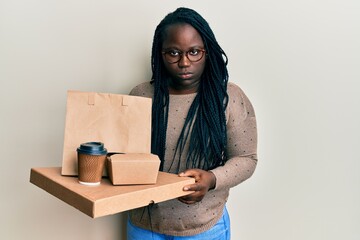 Sticker - Young black woman with braids holding take away food skeptic and nervous, frowning upset because of problem. negative person.