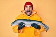 Handsome hispanic man with beard wearing fisherman equipment celebrating crazy and amazed for success with open eyes screaming excited.