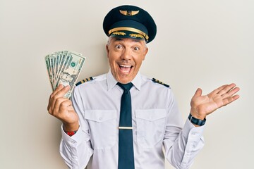 Sticker - Handsome middle age mature man wearing airplane pilot uniform holding dollars celebrating achievement with happy smile and winner expression with raised hand