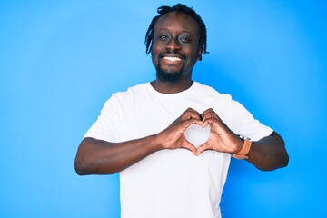 Poster - Young african american man with braids wearing casual white tshirt smiling in love showing heart symbol and shape with hands. romantic concept.