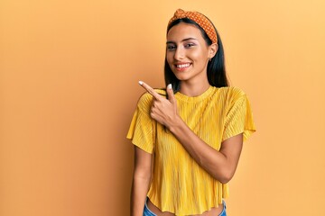 Poster - Young brunette woman wearing casual shirt and diadem smiling cheerful pointing with hand and finger up to the side