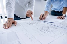 Midsection Of Architects Preparing Blueprint On Desk At Office