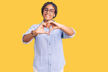 Sticker - Young african american woman with braids wearing casual clothes and glasses smiling in love doing heart symbol shape with hands. romantic concept.